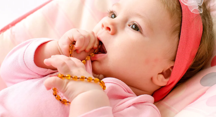 baby chewing on amber necklace